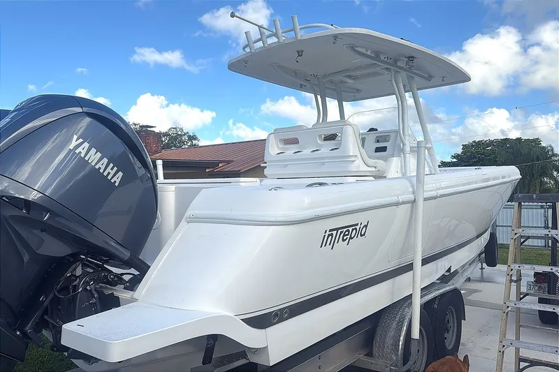 Slide: The Image of 2015 Intrepid 327 Center Console boat with Yamaha engine on trailer, under clear blue sky. - 12