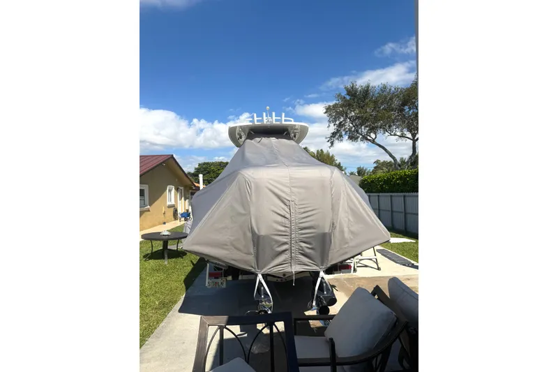 Slide: The Image of 2015 Intrepid 327 Center Console boat covered, parked outdoors under a clear blue sky. - 11