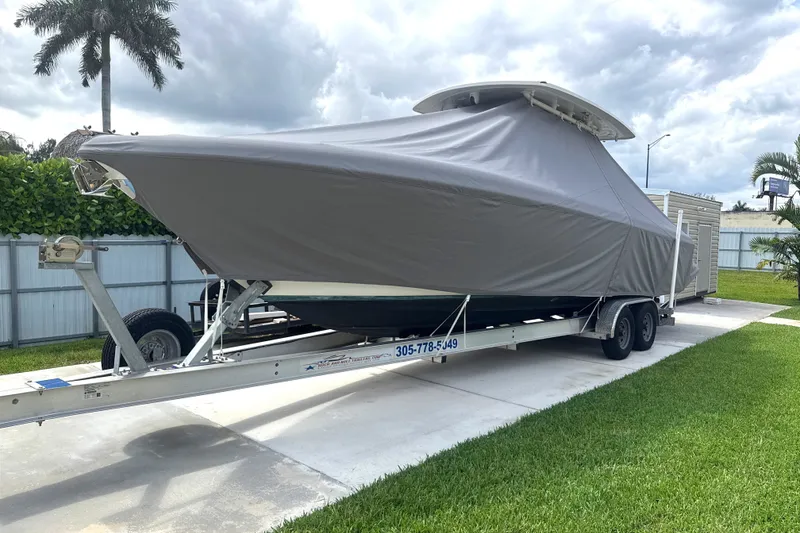Slide: The Image of 2015 Intrepid 327 Center Console boat covered on trailer in driveway. - 8