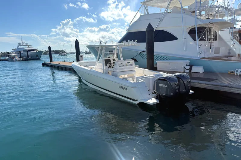 Slide: The Image of 2015 Intrepid 327 Center Console boat docked with Yamaha engines, under sunny skies. - 16