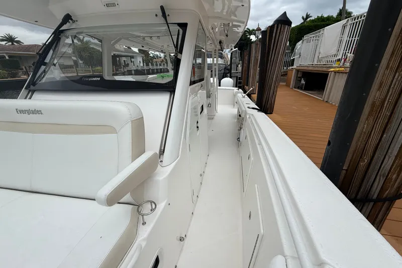 Slide: The Image of 2016 Everglades 435 Center Console boat docked, showcasing sleek white seating and deck design. - 19