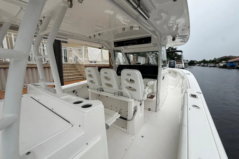 Slide: The Image of 2016 Everglades 435 Center Console boat interior with seating and helm, docked by a canal. - 25