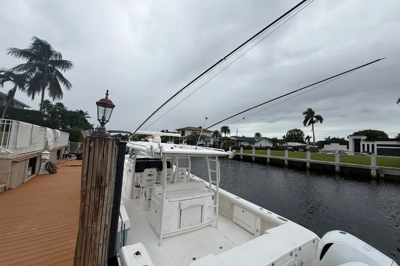 Slide: The Image of 2016 Everglades 435 Center Console boat docked by a canal with palm trees. - 26
