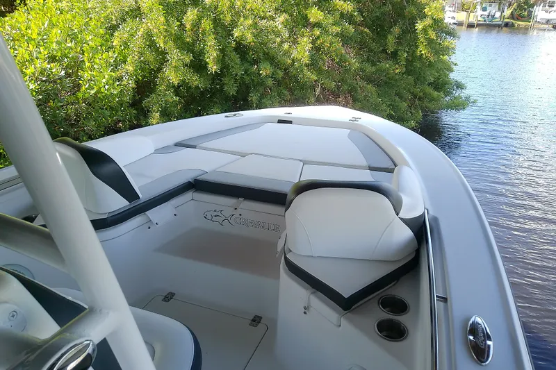 Slide: The Image of 2015 Crevalle 24 Bay boat interior with seating, near lush greenery and water. - 29