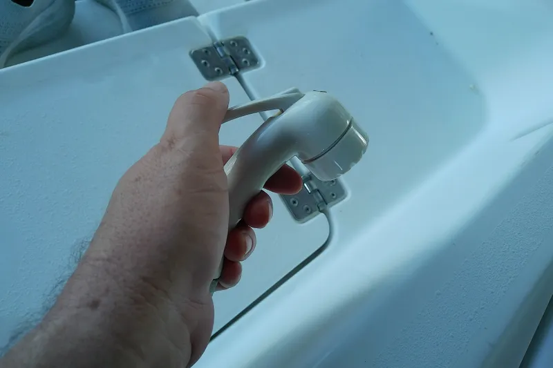 Slide: The Image of Hand holding a white showerhead on a 2015 Crevalle 24 Bay boat. - 34