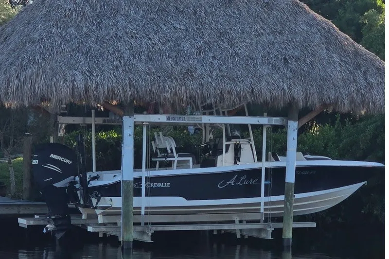 Slide: The Image of A 2015 Crevalle 23 Bay boat under a thatched roof, featuring a Mercury outboard motor. - 3