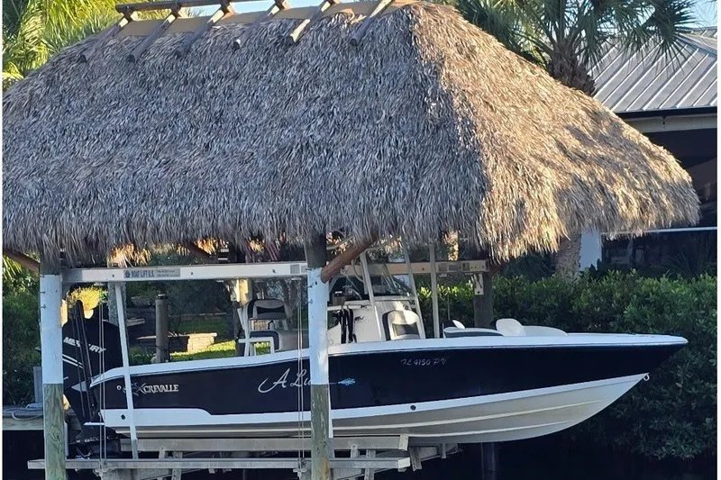 Slide: The Image of A 2015 Crevalle 23 Bay boat under a thatched roof, on a boat lift. - 4