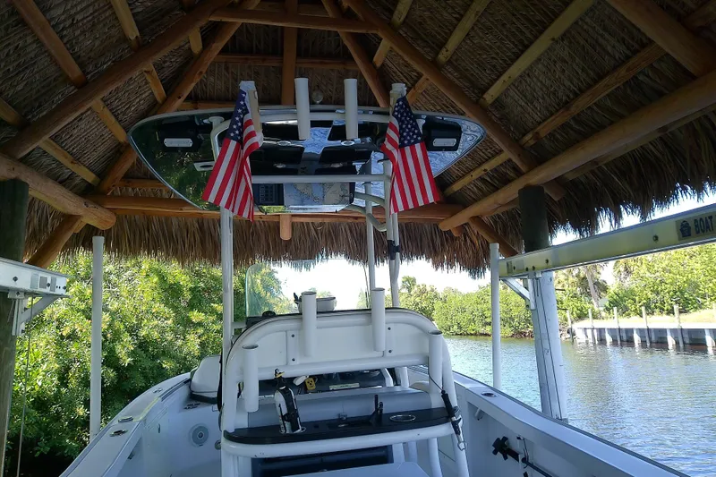 Slide: The Image of 2015 Crevalle 24 Bay boat under a thatched roof with American flags. - 10