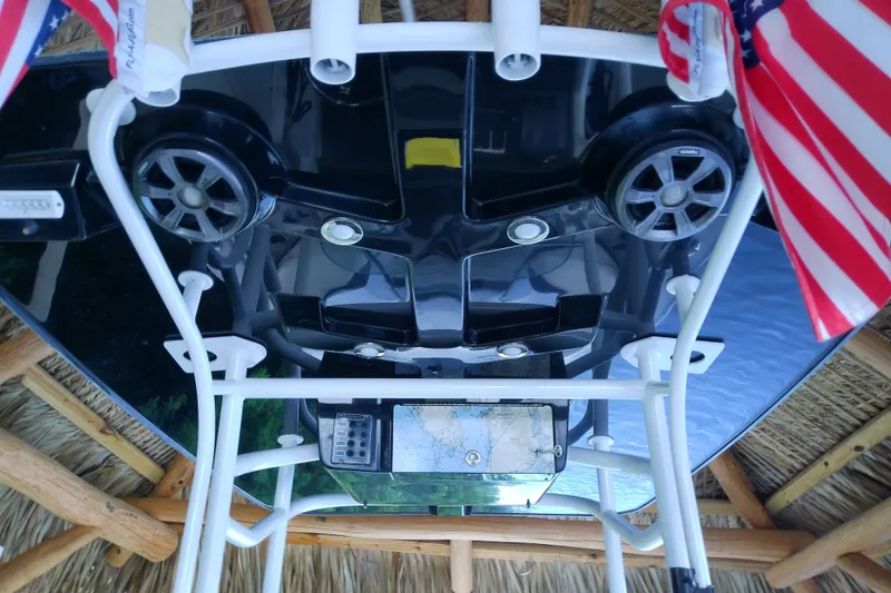 Slide: The Image of 2015 Crevalle 24 Bay boat with speakers and American flags under a thatched roof. - 37