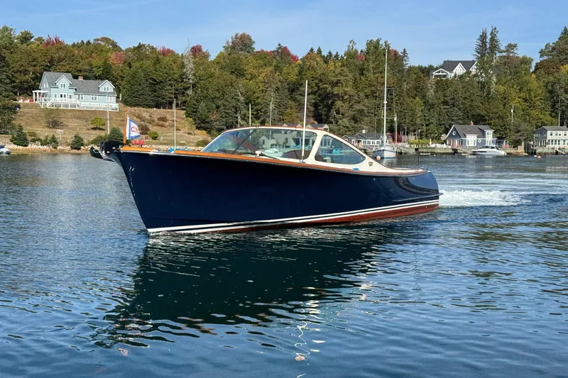 The Image of 2007 Hinckley Talaria 29R cruising on a scenic lake with waterfront homes. - 0