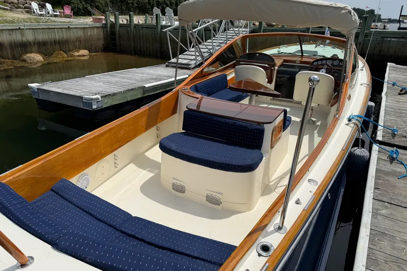 Slide: The Image of 2007 Hinckley Talaria 29R boat docked, featuring elegant wood trim and blue seating. - 13