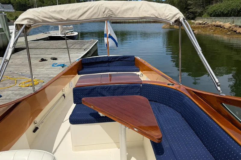 Slide: The Image of 2007 Hinckley Talaria 29R boat with blue seating and wooden table, docked by calm water. - 17