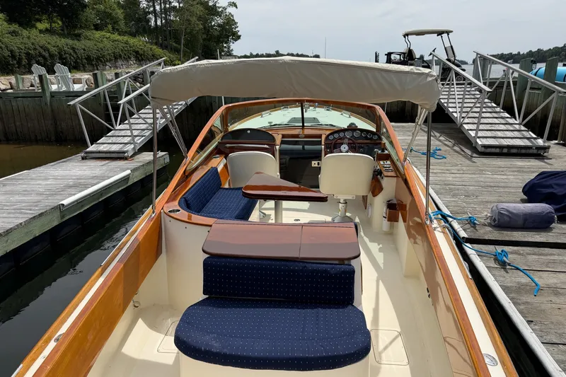 Slide: The Image of 2007 Hinckley Talaria 29R docked, featuring elegant woodwork and blue seating. - 14