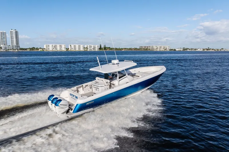 Slide: The Image of 2022 Intrepid 407 Nomad FE boat cruising on open water, city skyline in background. - 3