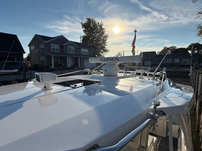 Slide: The Image of 2025 Tiara Yachts 34 LS with a sleek deck and Garmin equipment, set against a sunset near houses. - 30