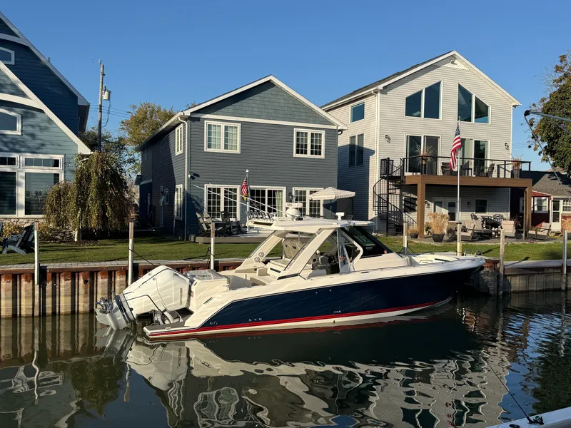 Slide: The Image of 2025 Tiara Yachts 34 LS docked in a calm canal, surrounded by modern houses. - 6