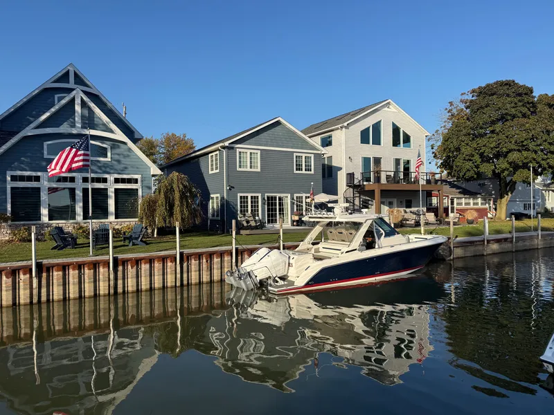 Slide: The Image of 2025 Tiara Yachts 34 LS docked in a calm canal, surrounded by modern homes. - 7