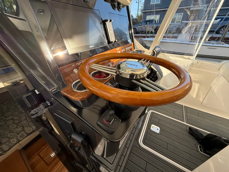Slide: The Image of The image shows the helm of a 2025 Tiara Yachts 34 LS with a sleek wooden steering wheel. - 25