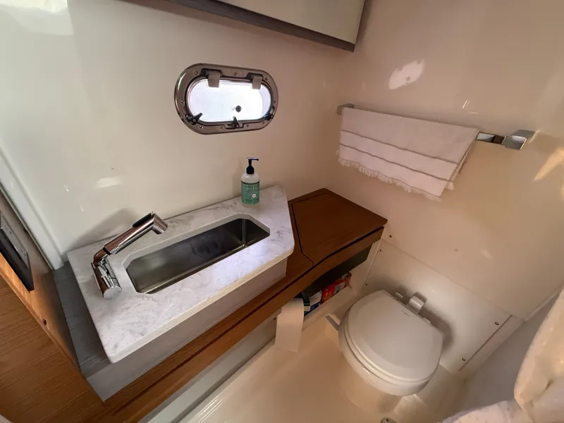 Slide: The Image of The image shows a sleek bathroom on a Tiara Yachts 34 LS. It features a sink, toilet, and small window. - 37