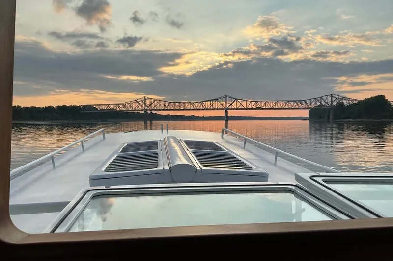 Slide: The Image of Sunset view from a 2009 Custom Thomas 50 Dutch Barge, with a bridge in the distance. - 1