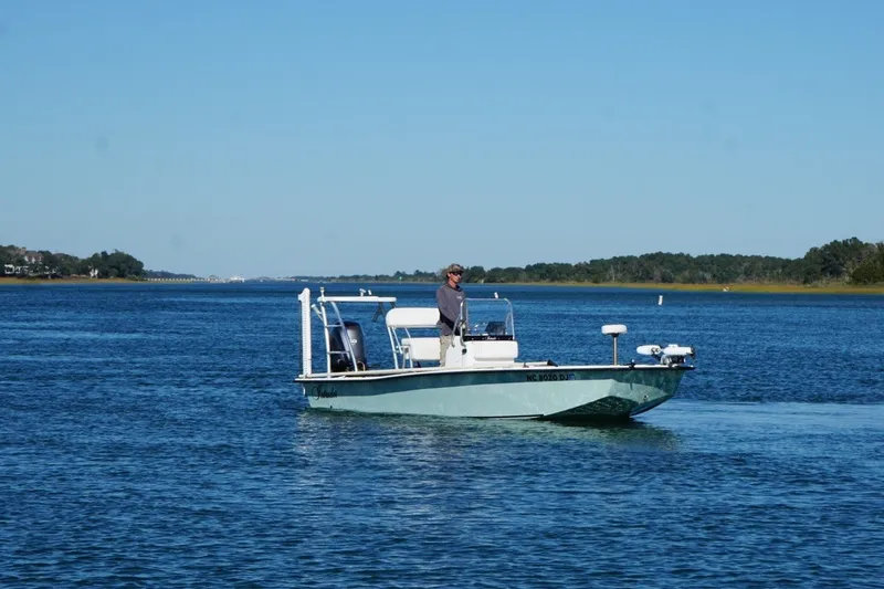 Slide: The Image of 2008 Intruder 198 boat on calm water with a person standing, clear blue sky. - 5