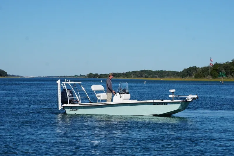 Slide: The Image of A 2008 Intruder 198 boat on a calm blue lake with a person onboard. - 2