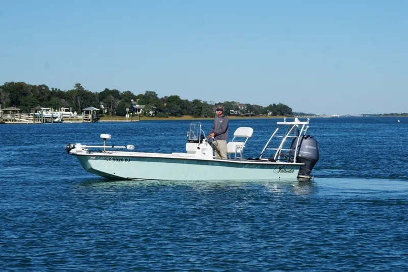 Slide: The Image of 2008 Intruder 198 boat cruising on a calm lake with a scenic shoreline backdrop. - 4