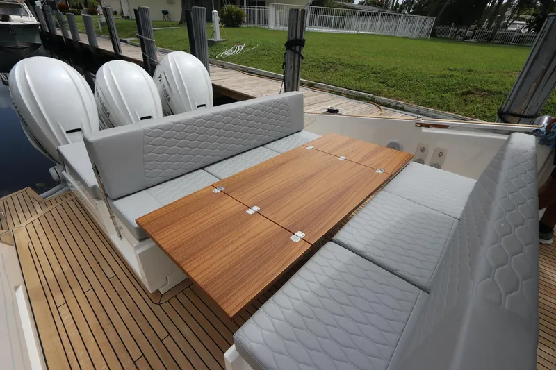 Slide: The Image of 2024 Astondoa 377 Coupe Outboard with sleek seating and wooden table on deck. - 32