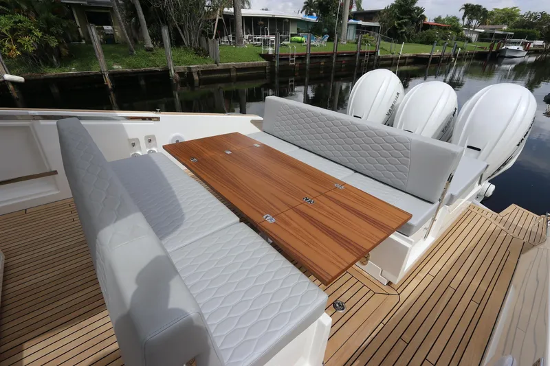 Slide: The Image of 2024 Astondoa 377 Coupe Outboard with elegant seating and wooden table on deck. - 31