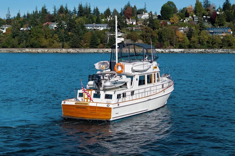 Slide: The Image of 2002 Grand Banks 46 Classic yacht cruising on a scenic blue lake with lush shoreline. - 2