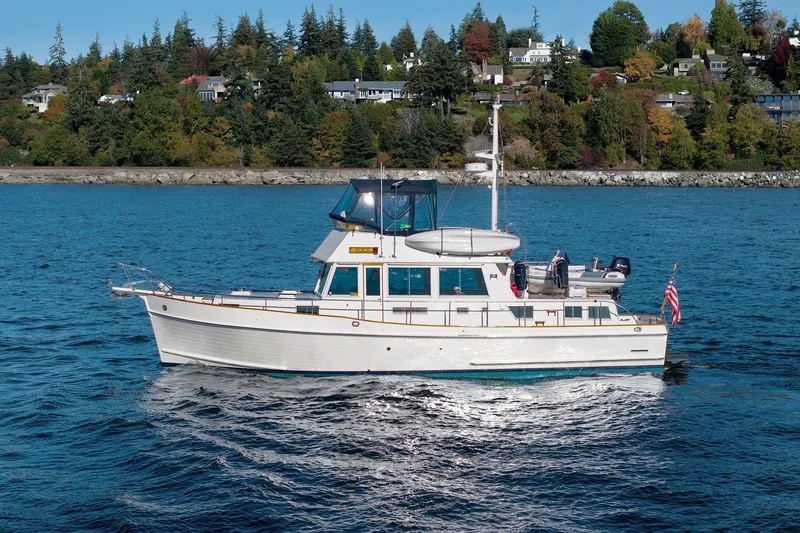 Slide: The Image of 2002 Grand Banks 46 Classic yacht cruising on a scenic blue lake with forested shoreline. - 5