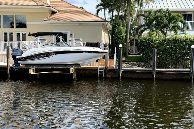 The Image of 2019 Hurricane SunDeck 2486 OB boat docked by waterfront home with lush greenery. - 5