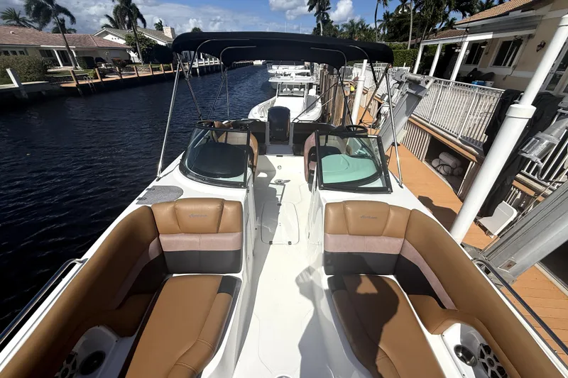 Slide: The Image of 2019 Hurricane SunDeck 2486 OB boat docked by waterfront homes, featuring spacious seating and canopy. - 11