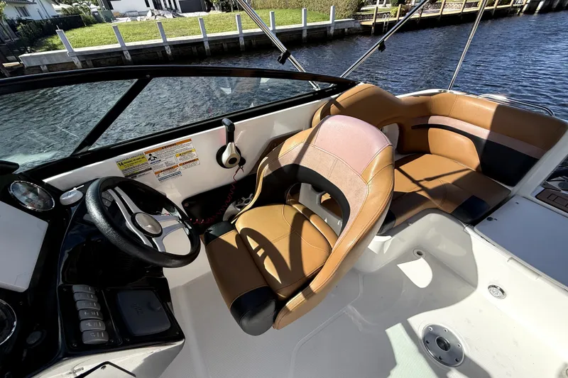 Slide: The Image of 2019 Hurricane SunDeck 2486 OB boat interior with tan seating and steering wheel. - 12