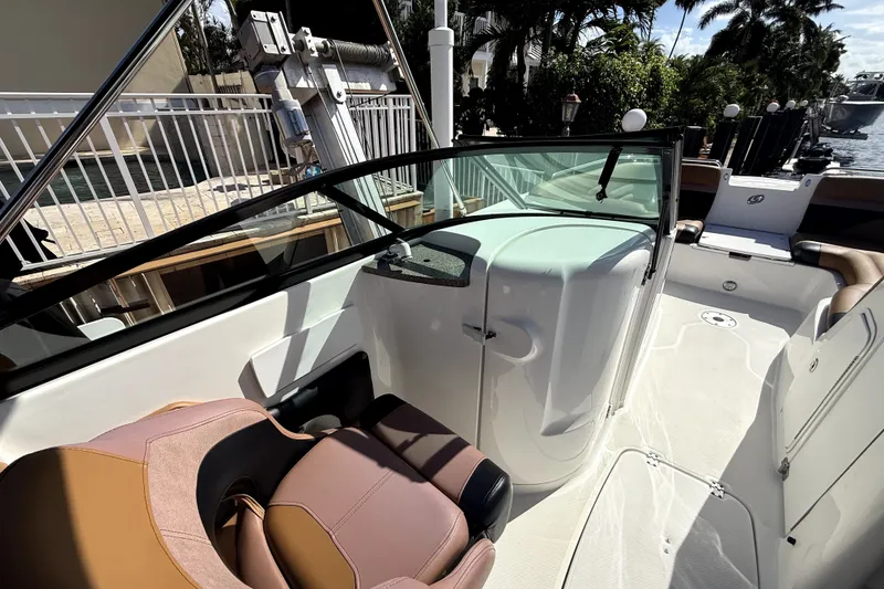 Slide: The Image of 2019 Hurricane SunDeck 2486 OB boat interior with seating and console, docked near water. - 10