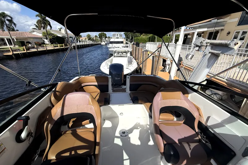Slide: The Image of 2019 Hurricane SunDeck 2486 OB boat interior with seating, docked by a canal. - 8