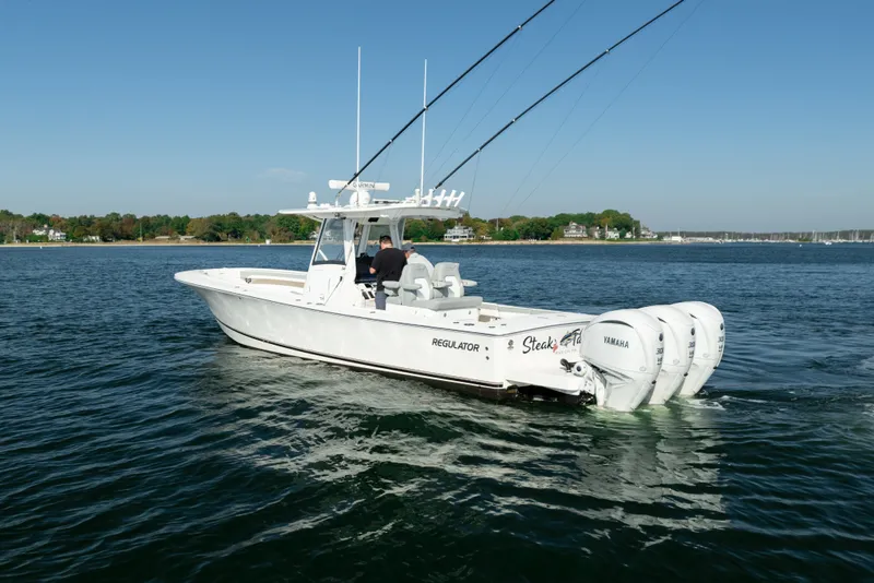 Slide: The Image of 2022 Regulator 34 CC on calm water with three outboard engines and fishing rods. - 5