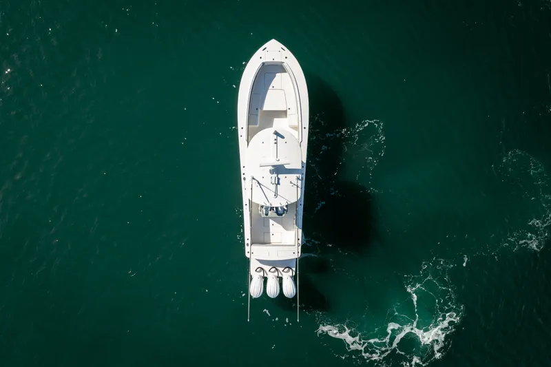 Slide: The Image of Aerial view of a white boat on calm water with three outboard engines. - 11