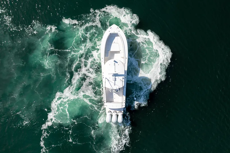 Slide: The Image of Aerial view of a white boat moving through green water, featuring three outboard engines. - 12