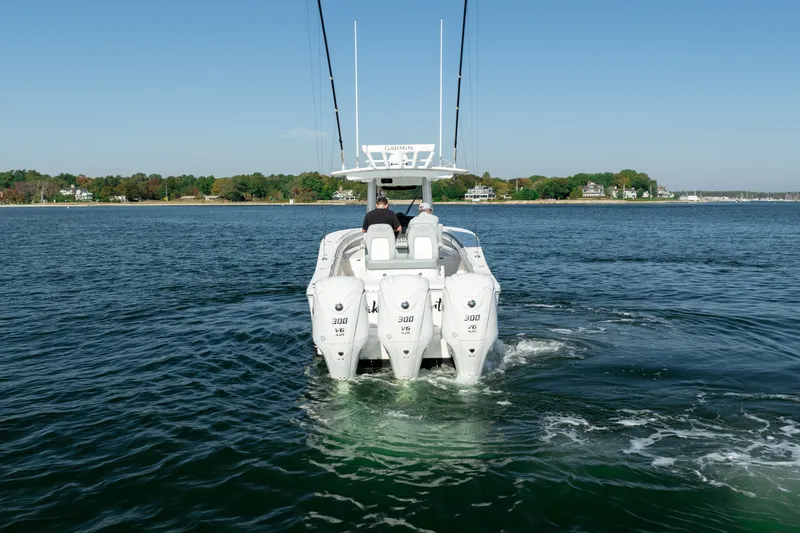 Slide: The Image of A 2022 Regulator 34 CC cruising on calm water. Three outboard engines are visible. - 6