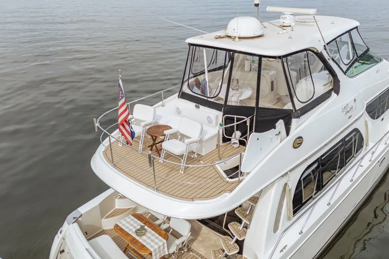 Slide: The Image of 2006 Carver 56 Voyager yacht on calm water, featuring spacious deck and seating area. - 15