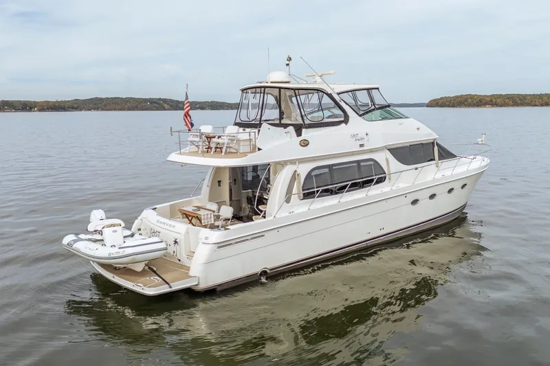 Slide: The Image of 2006 Carver 56 Voyager yacht on calm water, featuring a sleek design and spacious deck. - 23