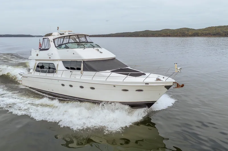 The Image of 2006 Carver 56 Voyager yacht cruising on a calm lake with scenic background. - 0