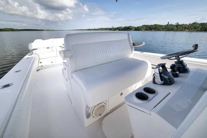 Slide: The Image of 2020 Bahama 41 boat interior with white seating and control panel on calm water. - 62