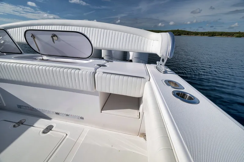 Slide: The Image of 2020 Bahama 41 boat interior with white seating and cup holders on calm water. - 45