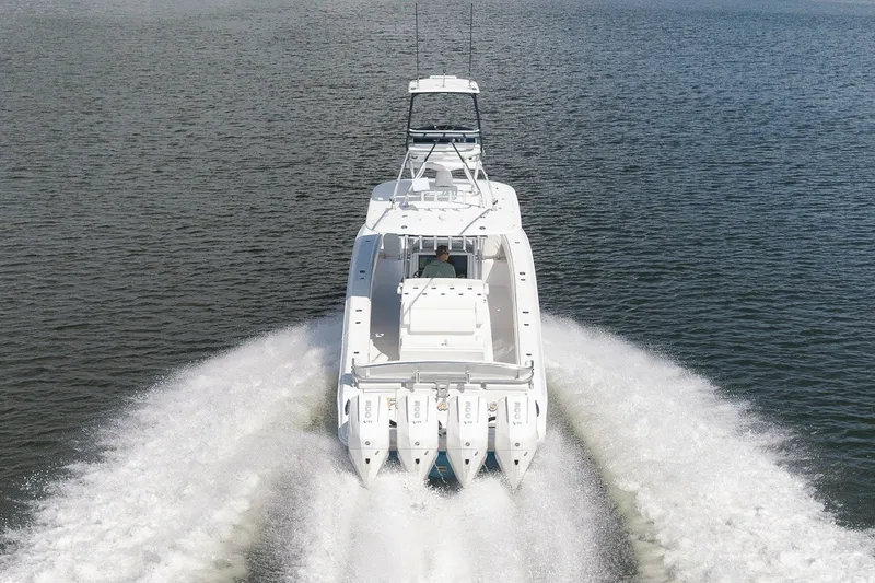 Slide: The Image of 2020 Bahama 41 boat cruising on open water, rear view with four engines. - 15