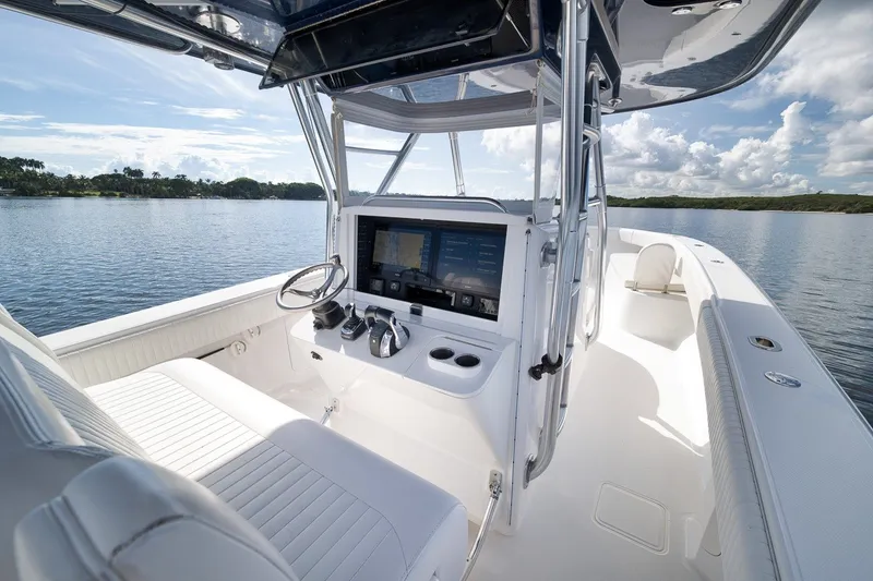 Slide: The Image of Interior view of 2020 Bahama 41 boat with modern dashboard and serene water backdrop. - 59