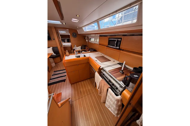 Slide: The Image of Interior of 2015 Jeanneau Sun Odyssey 469 yacht, featuring a modern kitchen and cozy seating area. - 45
