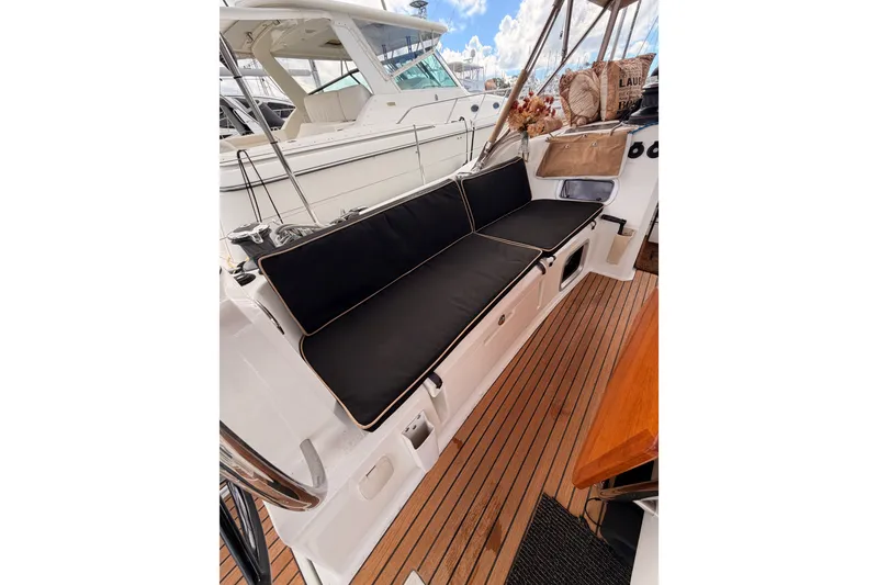 Slide: The Image of 2015 Jeanneau Sun Odyssey 469 yacht cockpit with black cushioned seating and wooden deck. - 35