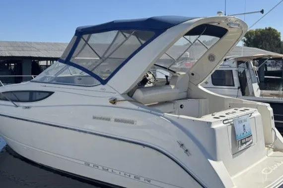 The Image of 2004 Bayliner 285 Cruiser boat docked with blue canopy and sleek design. - 1
